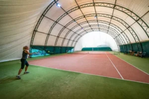 Kobieta odbijająca piłkę tenisową w hali tenisowej