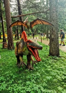 Dinozaur stojący w lesie wśród drzew