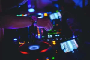 Zbliżenie na ręce DJ‑a pracujące na konsolecie z pokrętłami i przyciskami