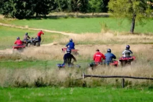 Grupa ludzi w oddali na łące jadąca na quadach