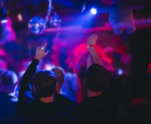 Ludzie bawiący się w klubie wśród kolorowych świateł