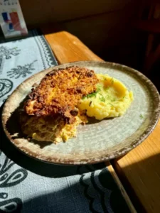 Kotlet panierowany z ziemniakami purée i surówką na talerzu