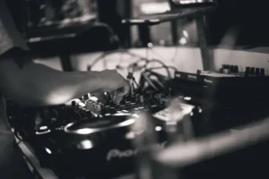 Ręce DJ‑a obsługującego pokrętła i przyciski na konsolecie DJ‑skiej