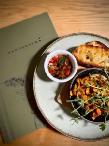 Sałatka z grzankami na talerzu obok menu Restauracji Regionalnej Zawierucha w Zakopanem
