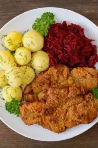 Kotlet panierowany z ziemniakami i buraczkami na talerzu