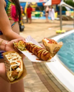Dzieci trzymające hot dogi w rękach na tle basenu