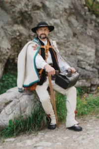 Doktor Narcyz w stroju góralskim siedzący na kamieniu