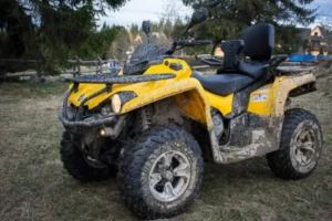 Brudny quad stojący na trawie po jeździe terenowej