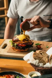 Osoba polewająca hamburgera sosem