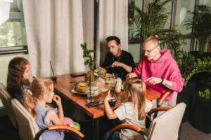 Dzieci jedzące frytki przy stole oraz dwóch mężczyzn spożywających posiłek w Bistro Termy Zakopiańskie