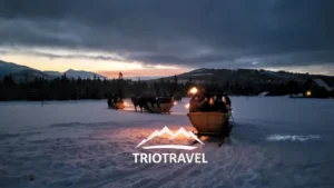 Kulig zimowy z pochodniami i widocznym logo Trio Travel